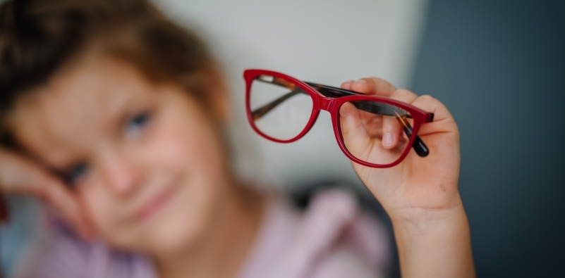 little girl holding her eyeglasses